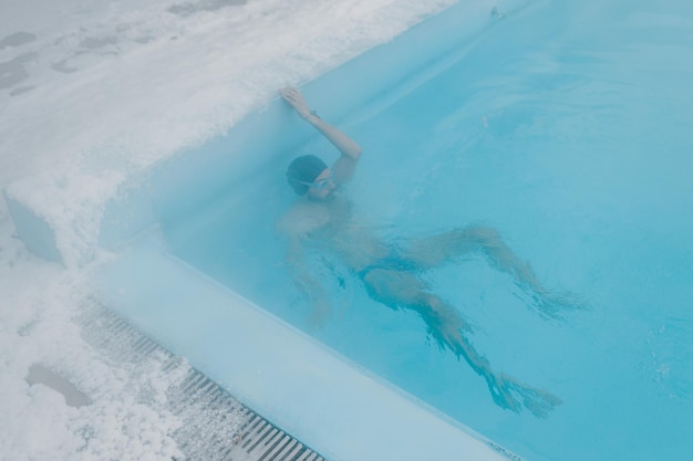 Ajuste nadador entrenamiento masculino nadar en piscina abierta de invierno con niebla Concepto de spa geotérmico al aire libre