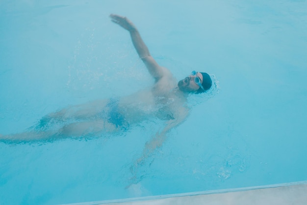 Ajuste nadador entrenamiento masculino nadar en piscina abierta de invierno con niebla Concepto de spa geotérmico al aire libre