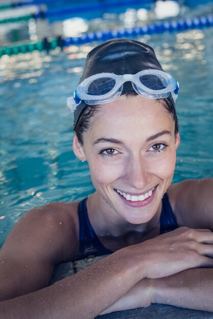 Ajuste nadador sonriendo a la cámara en la piscina