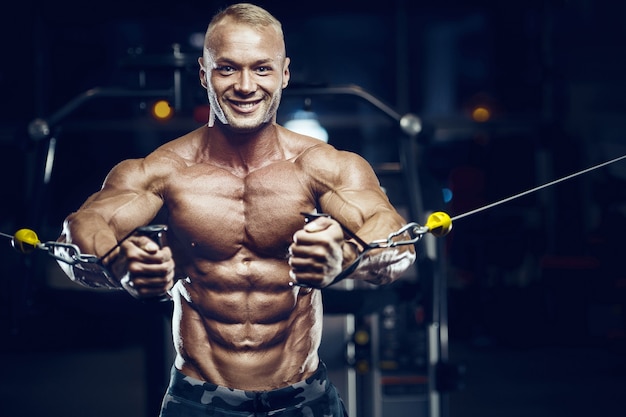 Ajuste os músculos do braço de treinamento do homem no ginásio. Exercício de bombeamento de bíceps.