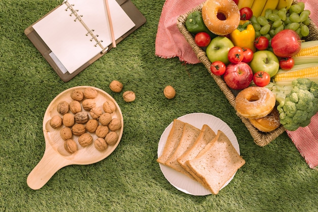 Ajuste de picnic de verano en el césped con cesta de picnic abierta, fruta, ensalada y tarta de cerezas