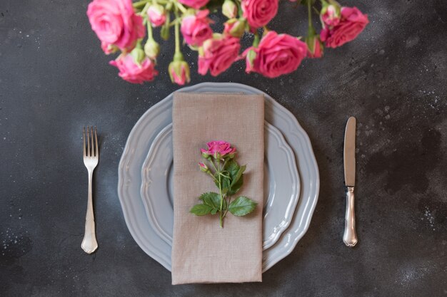 Ajuste romântico da tabela com as rosas cor-de-rosa como a decoração, o dishware do vintage, a pratas, e as decorações.