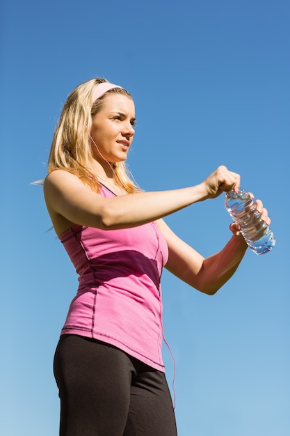 Ajuste rubia abriendo su botella de agua