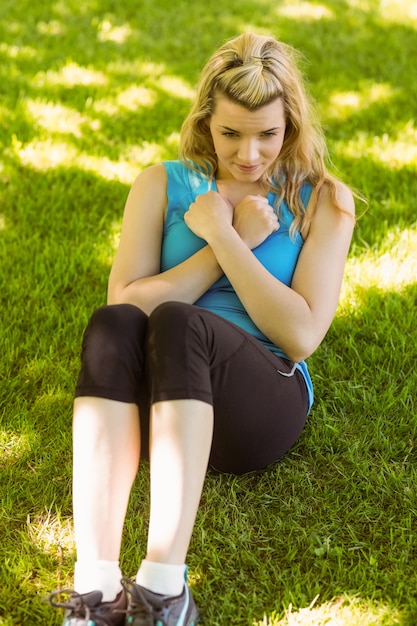 Ajuste rubia haciendo sentadillas en el parque