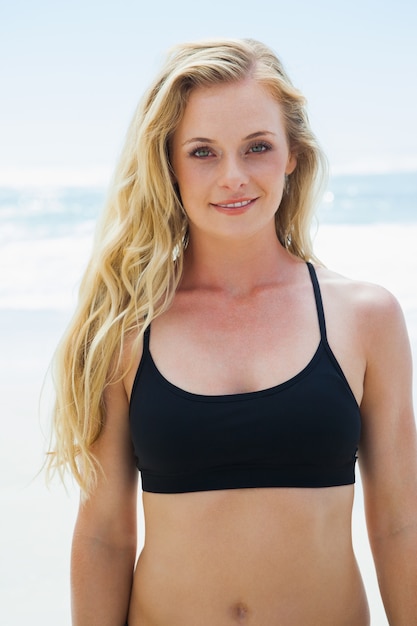 Ajuste rubia sonriendo a la cámara en la playa