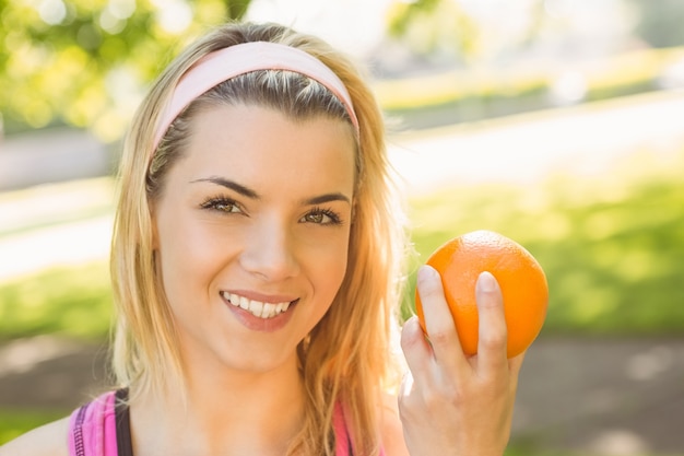 Ajuste rubia sosteniendo una naranja