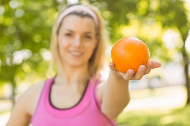 Ajuste rubia sosteniendo una naranja