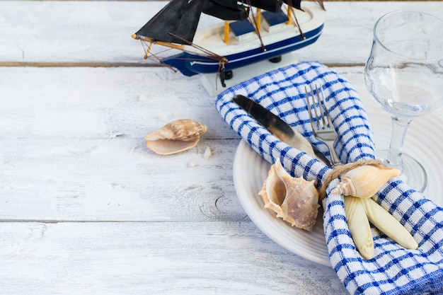Ajuste de la tabla de estilo marino en un plato con conchas marinas