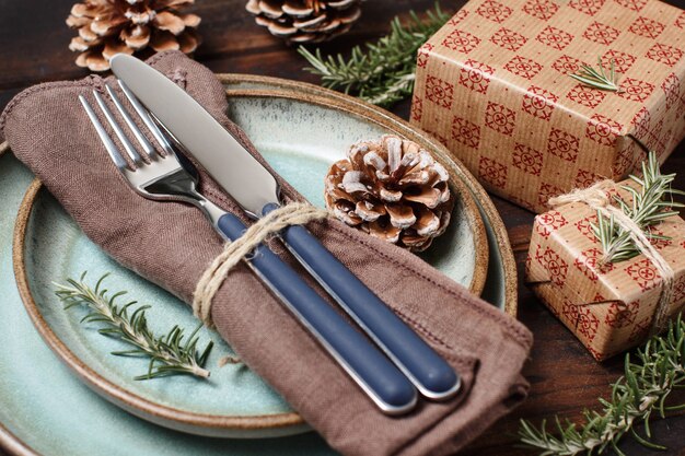 Ajuste de la tabla festiva rústica en la mesa de madera con cajas de regalo envueltas y piñas