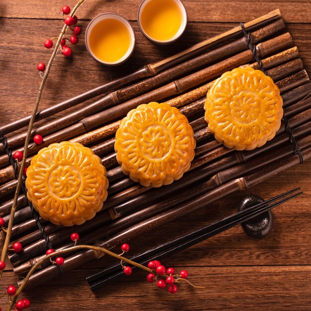 Ajuste de la tabla Mooncake Mooncake - pastelería tradicional china con tazas de té sobre fondo de madera, concepto del Festival del Medio Otoño, vista superior, endecha plana