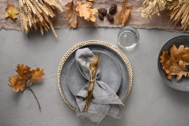 Ajuste de la tabla de otoño con cosecha de temporada y decoración dorada en gris.