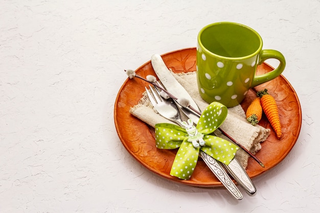 Ajuste de la tabla de Pascua en fondo blanco texturizado de la masilla. Plantilla de tarjeta de vacaciones de primavera. Cubiertos, taza, servilleta vintage, huevo, zanahoria, conejito