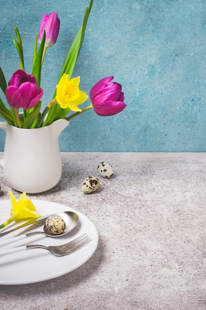 Ajuste de la tabla de Pascua de primavera con flores y huevos sobre un fondo gris