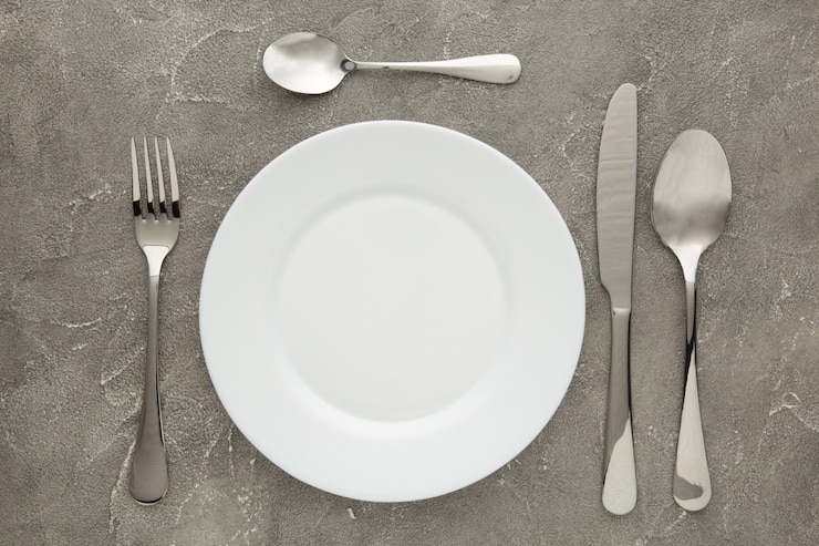 Foto ajuste de la tabla con plato blanco y cubiertos