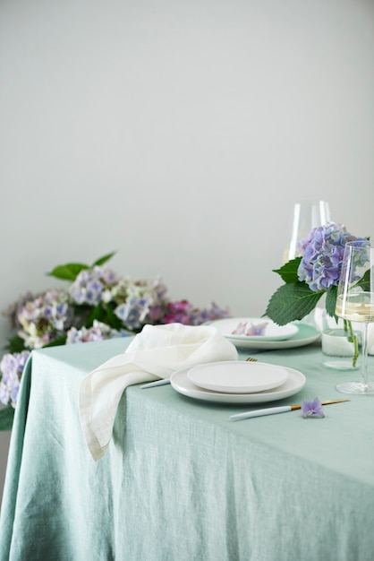 Ajuste de la tabla con platos de cerámica hechos a mano sobre mantel de lino verde y flores. Concepto de fiesta