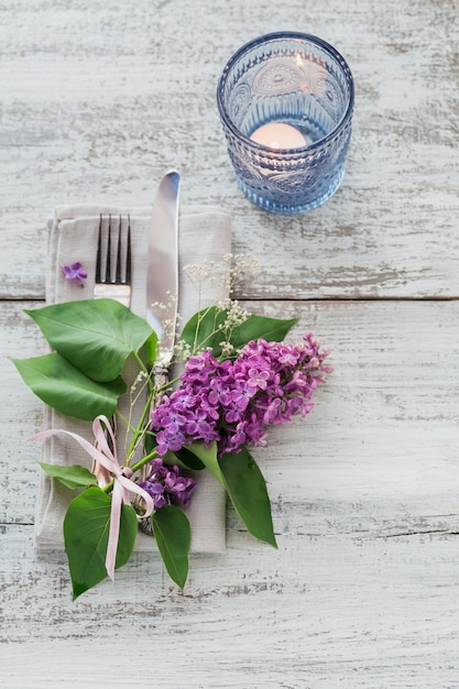 Ajuste de la tabla rústica con flores lilas en la mesa de madera clara