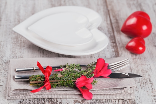 Ajuste de la tabla rústica con flores de tomillo y ciclamen y forma de decoración de corazón en la mesa de madera clara con copyspace