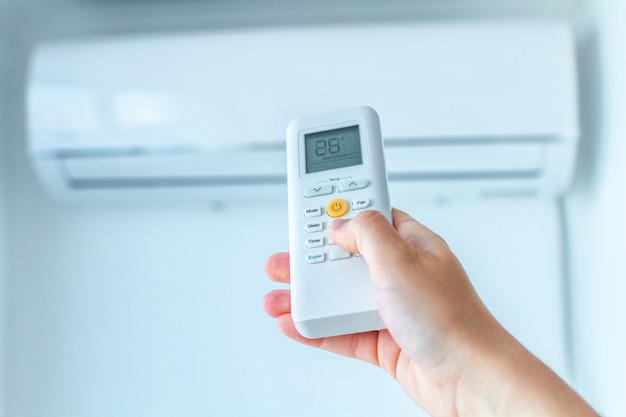 Ajuste de temperatura del aire acondicionado con control remoto en la habitación de su casa.