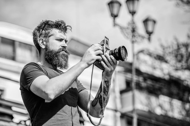 Ajustes manuales Fotógrafo con cámara vintage Blogger moderno Creador de contenido Fotógrafo hipster con barba Fotógrafo con barba y bigote Hombre con barba larga tomando fotos