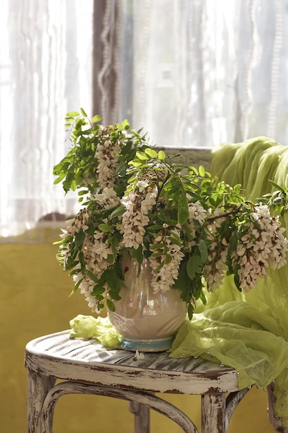 Akazienblüten in weißer Vase. Stillleben mit Akazienblüten auf Vintage-Shair.