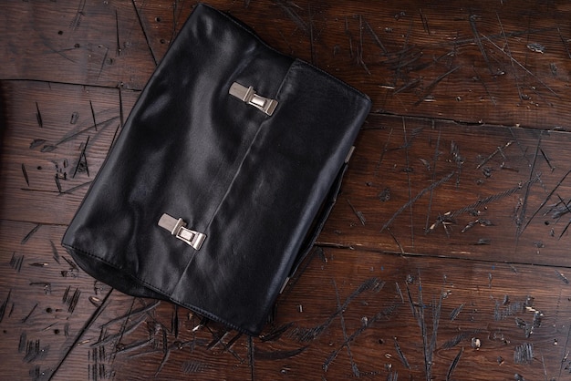 Aktentasche aus Leder mit Eisenverschlüssen, Aktentasche aus schwarzem Leder auf dem Tisch