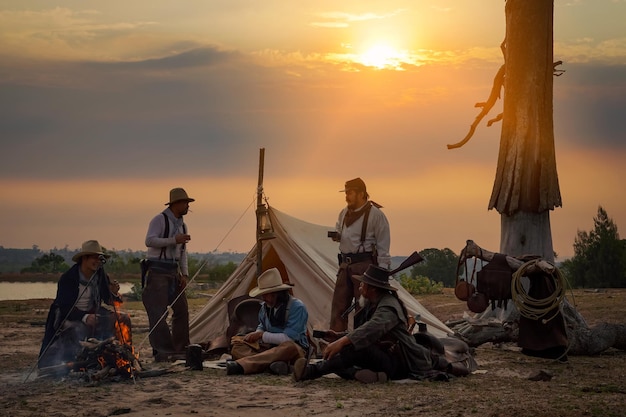 Aktionsbild Vintage-Stil der Cowboy-Gruppe Lehnen Sie sich entspannt zurück und trinken Sie morgens einen Kaffee beim Camping im goldenen Licht der Morgensonne