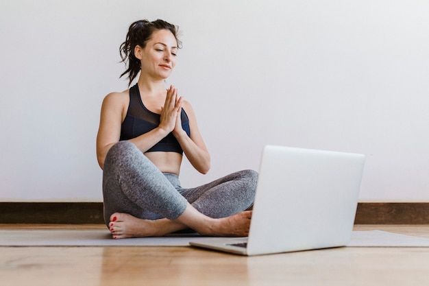 Aktive Frau lernt Yoga online über einen Laptop