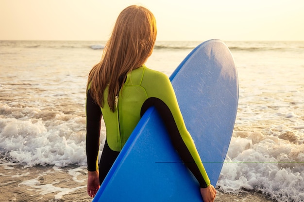 Aktive Frauen mit Surfbrett genießen Wassersport im Urlaub. Sportmädchen im Surfschullehrer des Windsurfens. Touristisches weibliches Modell in einem Taucheranzug Neoprenanzug am Strand im Indischen Ozean