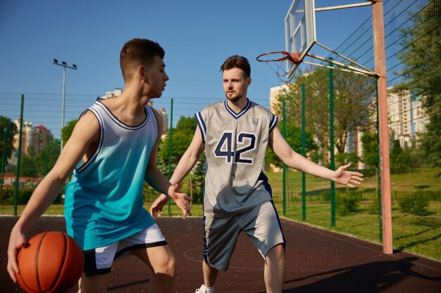 Aktive junge Männer spielen Basketball auf dem Straßenplatz. Sport und Hobby-Erholung für Freunde am Wochenende