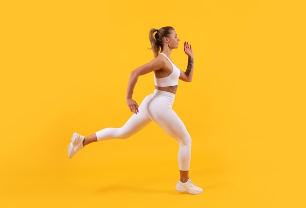Aktive Sportfrau, die auf gelbem Hintergrund läuft