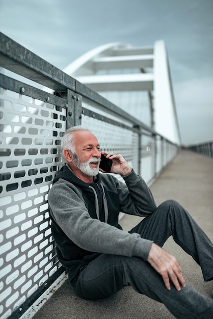 Aktiver älterer Mann, der eine Pause macht und am Telefon spricht.