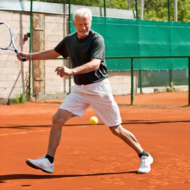 Aktiver älterer Mann, der Tennis spielt