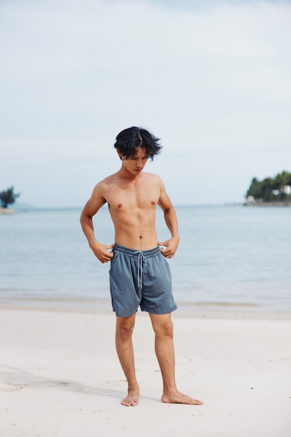 Aktiver asiatischer Athlet, der im Sommer bei Sonnenuntergang am Strand läuft