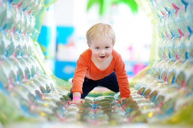 Aktiver glücklicher Kleinkindjunge, der zuhause am Spielplatz spielt