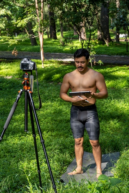 Aktiver gutaussehender männlicher Yogi geht vor oder nach dem Training in einem Park spazieren Wald spazieren Junger hispanischer athletischer Mann Yoga-Kurs mit einer Fitnessmatte