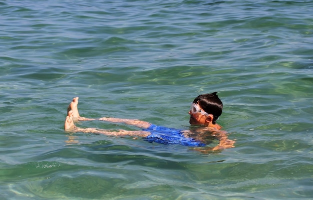 Foto aktiver junge, der im meerwasser schwimmt.