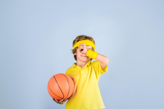 Aktiver Lebensstil-Basketball-Sportjunge mit Basketballball-Sportjunge zeigt Zeichen ok, Kind hält Ball