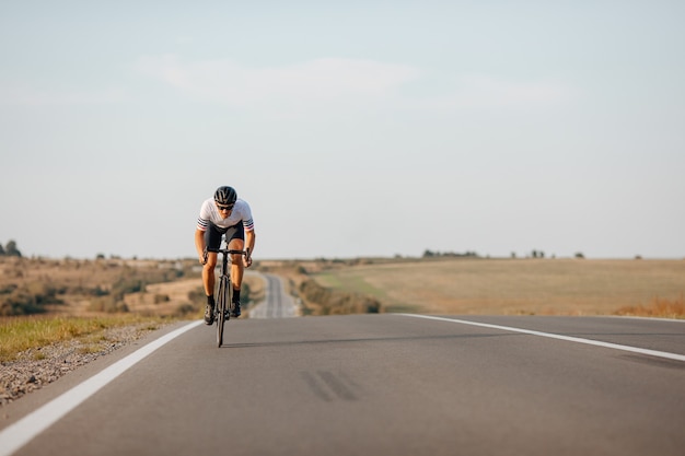 Aktiver männlicher Athlet, der schwarzen Helm und Brille beim Radfahren auf Asphaltstraße trägt