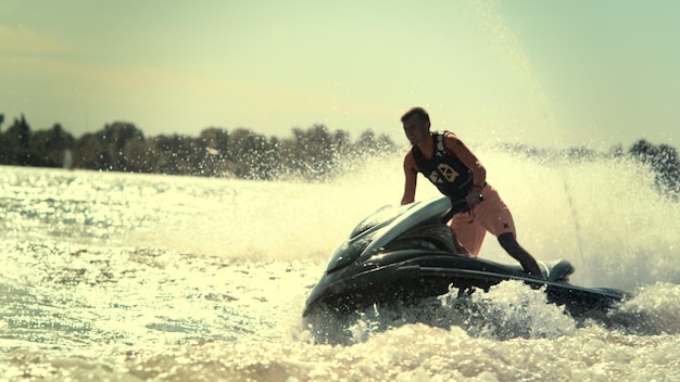 Aktiver Mann auf Jetski, der sich bei Sonnenuntergang in Zeitlupe auf dem Fluss vergnügt