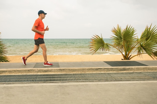 Aktiver Mann in Sportkleidung, Aufwärmtraining, Lauf am Meeresstrand, Joggen im Freien am Meer