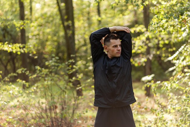 Aktiver Sportler trainiert Aufwärmübungen oder Stretching im Herbstwald Gesunder Lebensstil Training im Freien