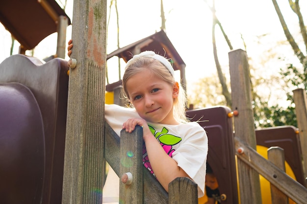 Aktives blondes kleines mädchen, das auf einem spielplatz spielt