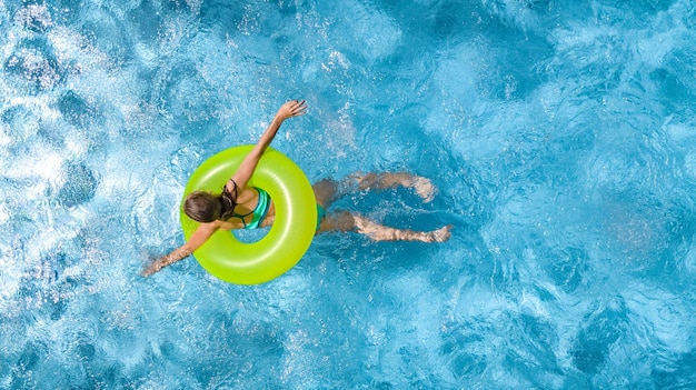 Aktives junges Mädchen im Pool Luftbild von oben, Teenager schwimmt auf aufblasbarem Ring