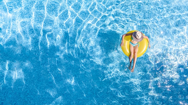 Aktives junges Mädchen im Schwimmbad Luftdraufsicht von oben Kind entspannt und schwimmt auf aufblasbarem Ringkrapfen und hat Spaß im Wasser im tropischen Urlaubsort des Familienurlaubs