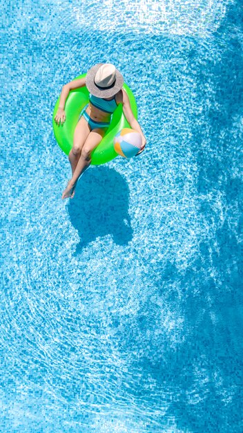 Aktives junges mädchen in der luftaufnahme des schwimmbades von oben, kind entspannt sich und schwimmt auf aufblasbarem ringkrapfen und hat spaß im wasser im familienurlaub, tropischer ferienort