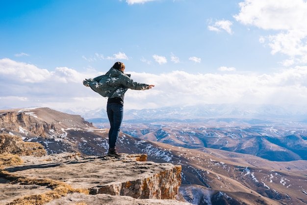 Aktives junges Mädchen in einer warmen Jacke reist durch die Berge, genießt die Natur und die saubere Luft