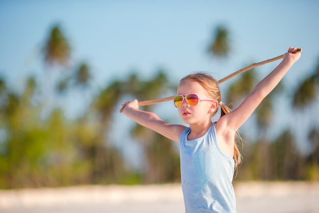 Aktives kleines Mädchen auf dem weißen Strand, der Spaß hat. Nahaufnahmekinderhintergrund das Meer