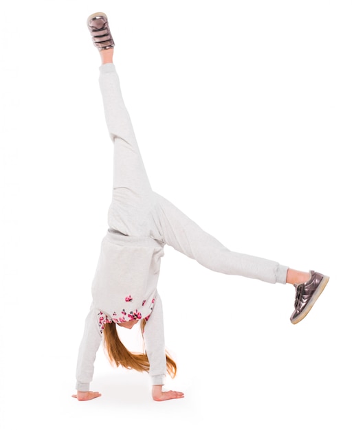 Aktives kleines Mädchen auf weißem Hintergrund, das einen Handstand tut