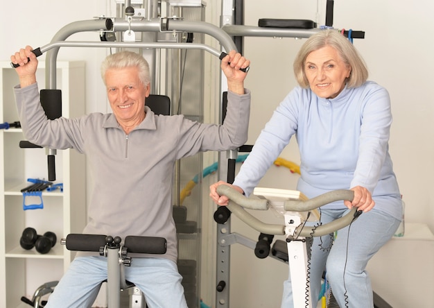 Aktives lächelndes älteres Paar, das im Fitnessstudio trainiert