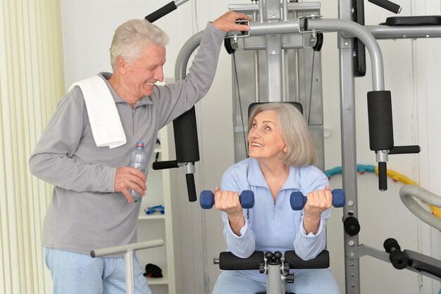 Aktives lächelndes älteres Paar, das im Fitnessstudio trainiert